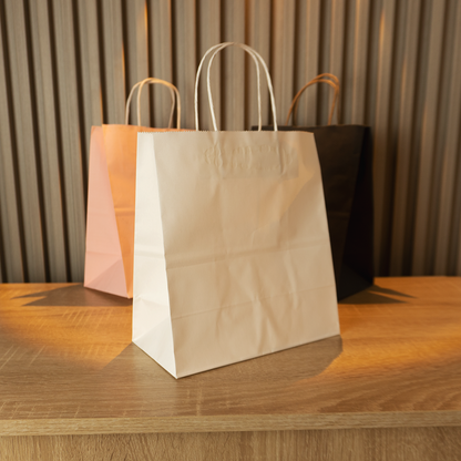 Bolsas kraft lisas con manigueta en varios colores, sobre mesa de madera