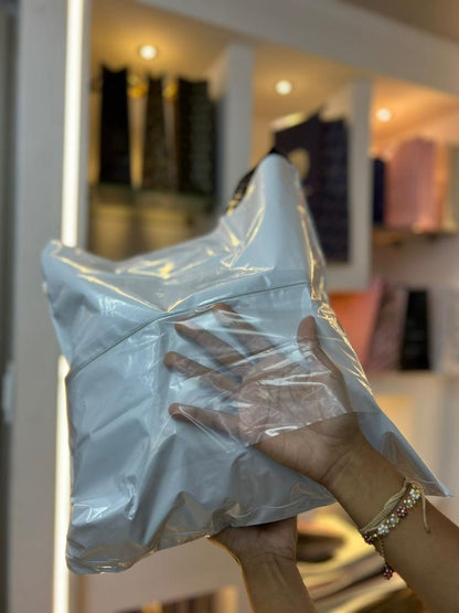 Bolsa de seguridad negra con logo blanco de una tienda de ropa y etiqueta colgante