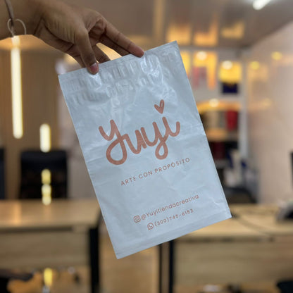 Bolsa de seguridad blanca con logo de joyería en rosa, sostenida en mano